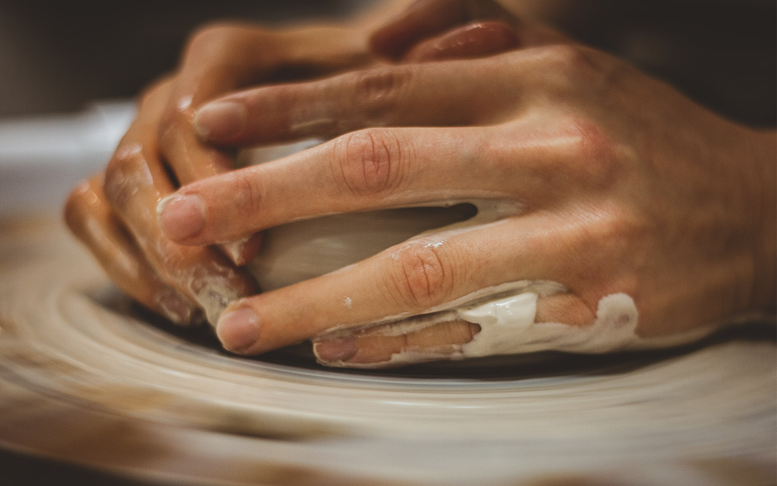 Potters hands lightly shaping a bowl out of clay