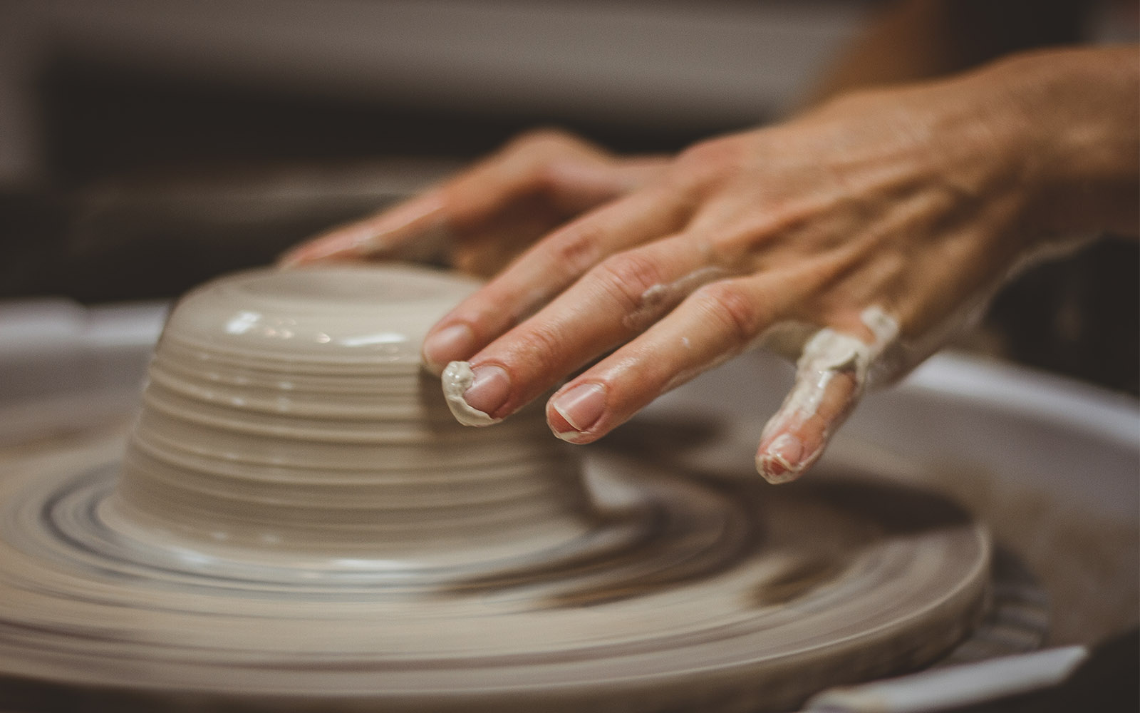 Potters hands lightly shaping a bowl out of clay