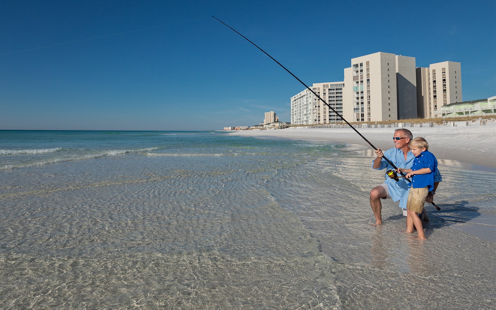 Grandpa teaching young grandson fishing along the gulf of Mexico