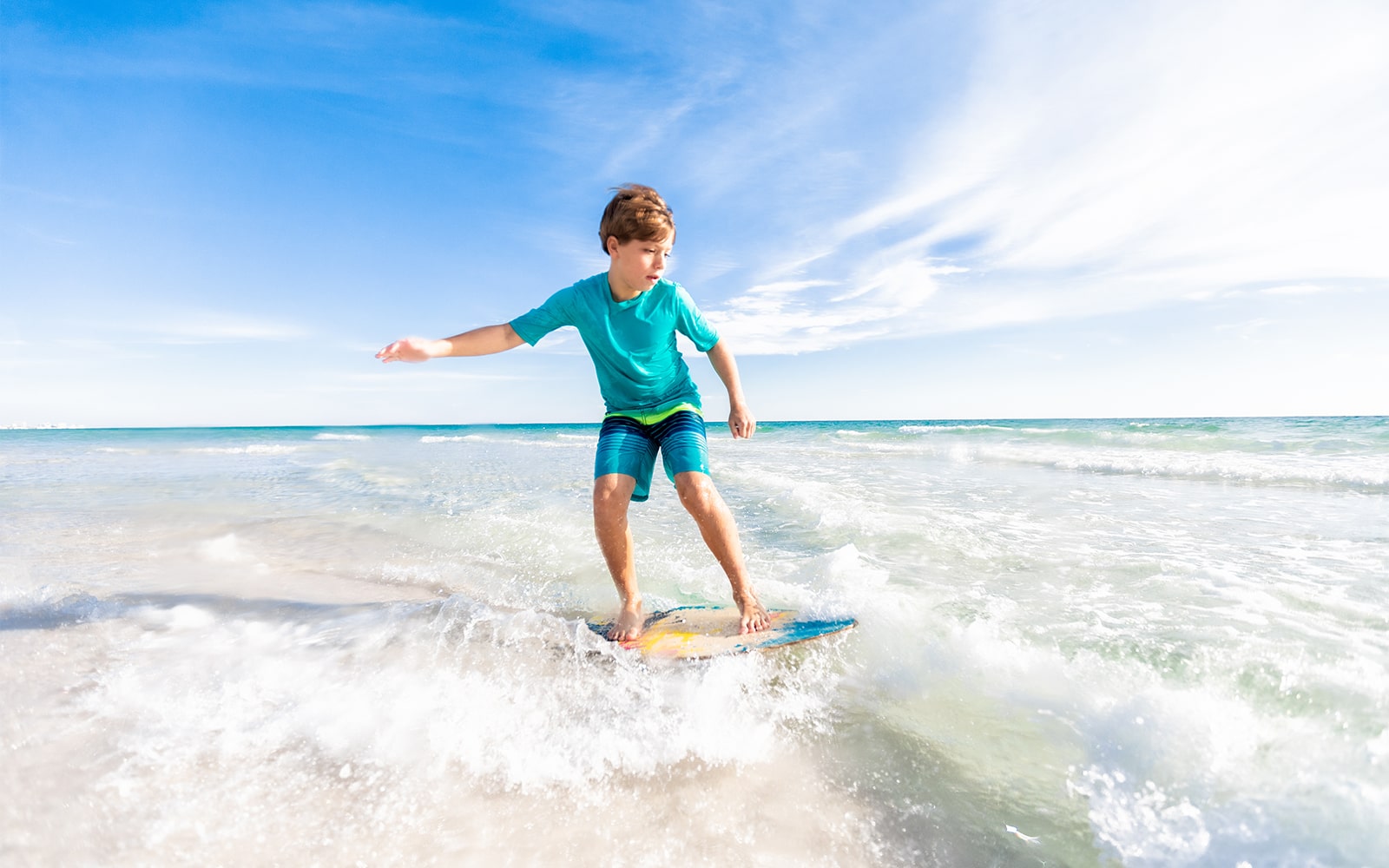 Kid skim boarding against waves in the gulf of Mexico