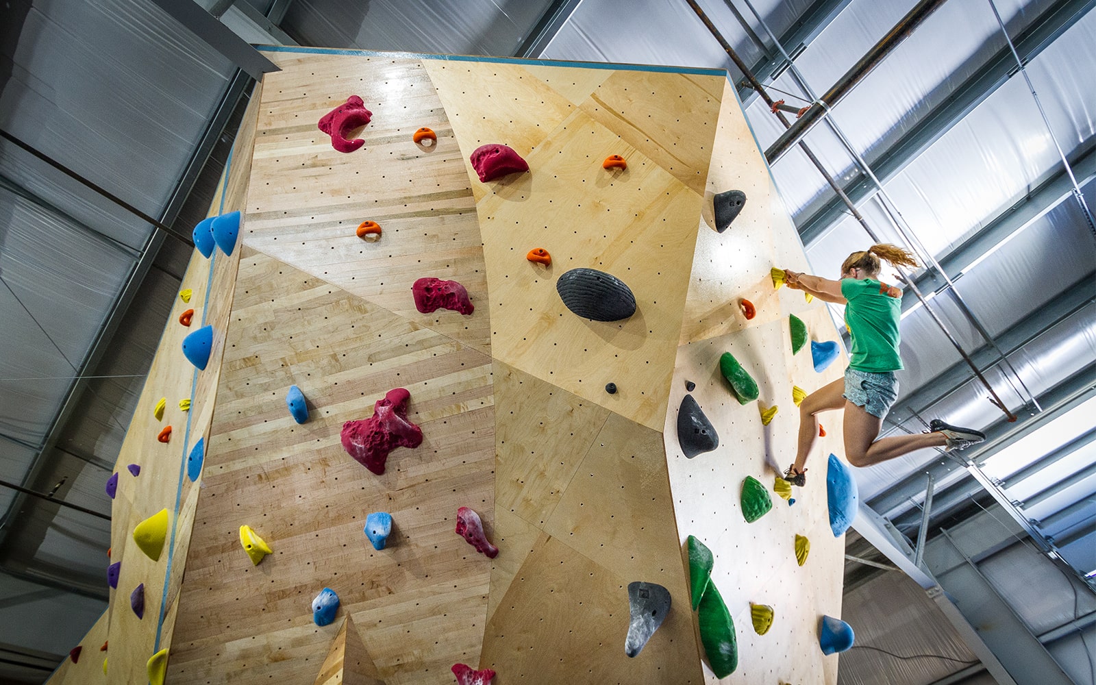 Woman reaching the top of climbing wall at indoor rock climbing gym