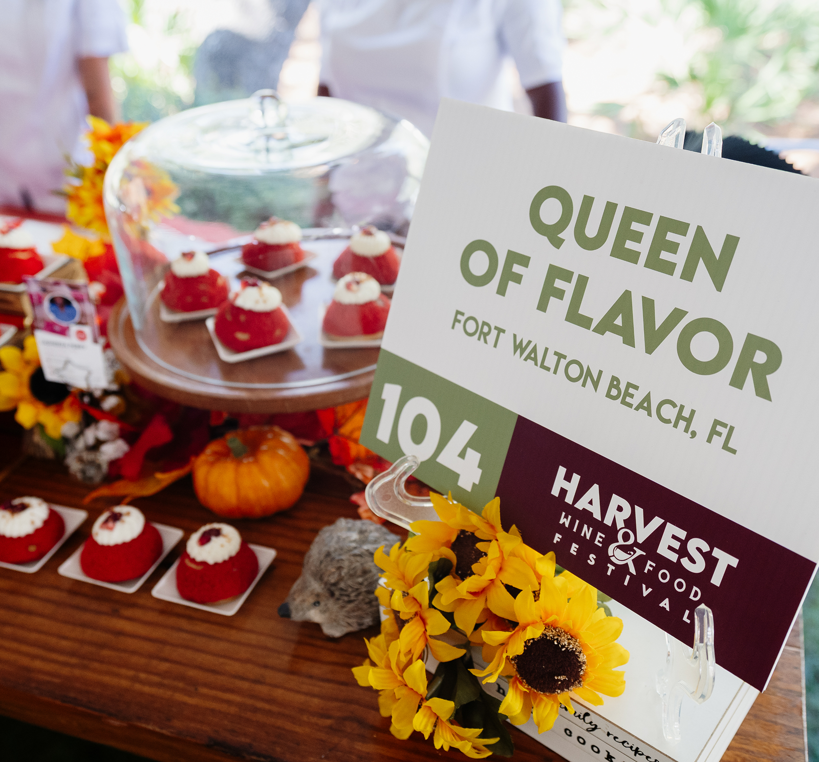Cupcakes in a glass cloche next to "queen of flavor" sign