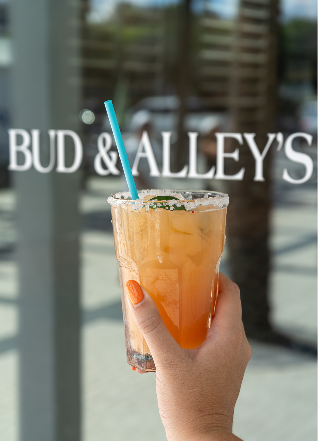 Golden-orange drink in front of Bud & Alley's window sign