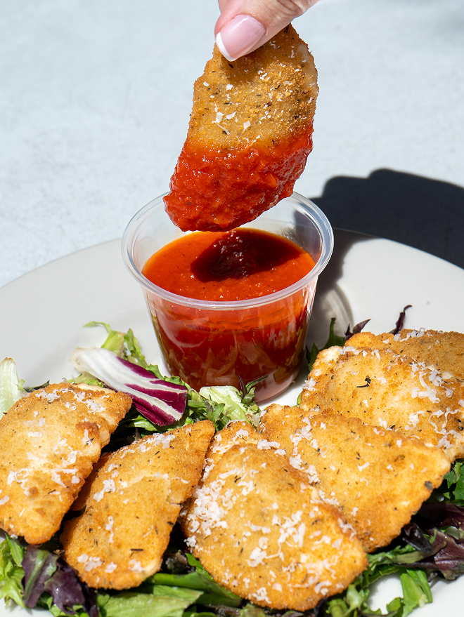 Fried Ravioli being dipped in marinara sauce