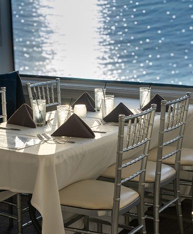 A set table in front of a window over the water